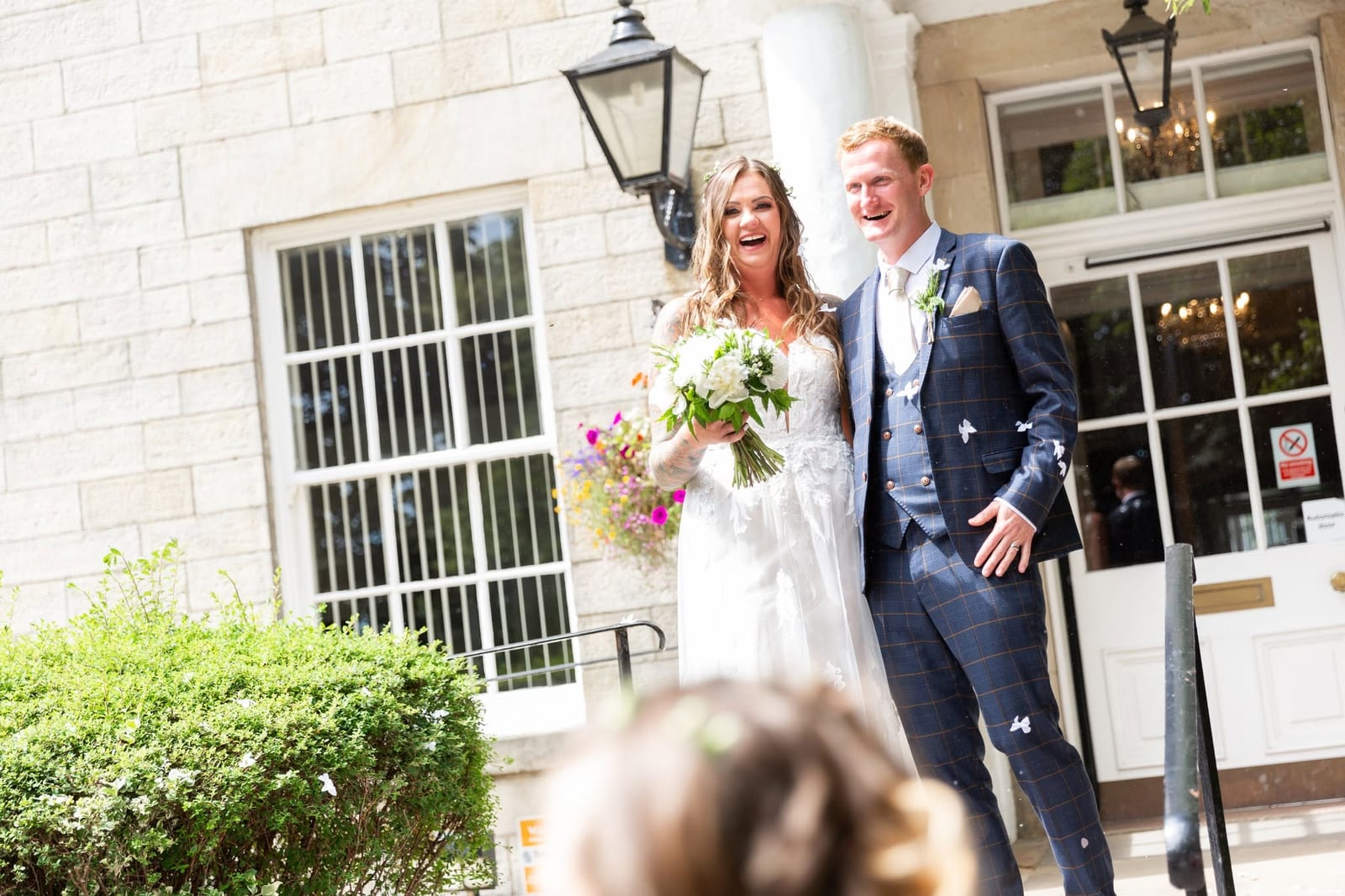 A newly married couple laughing outside their wedding venue