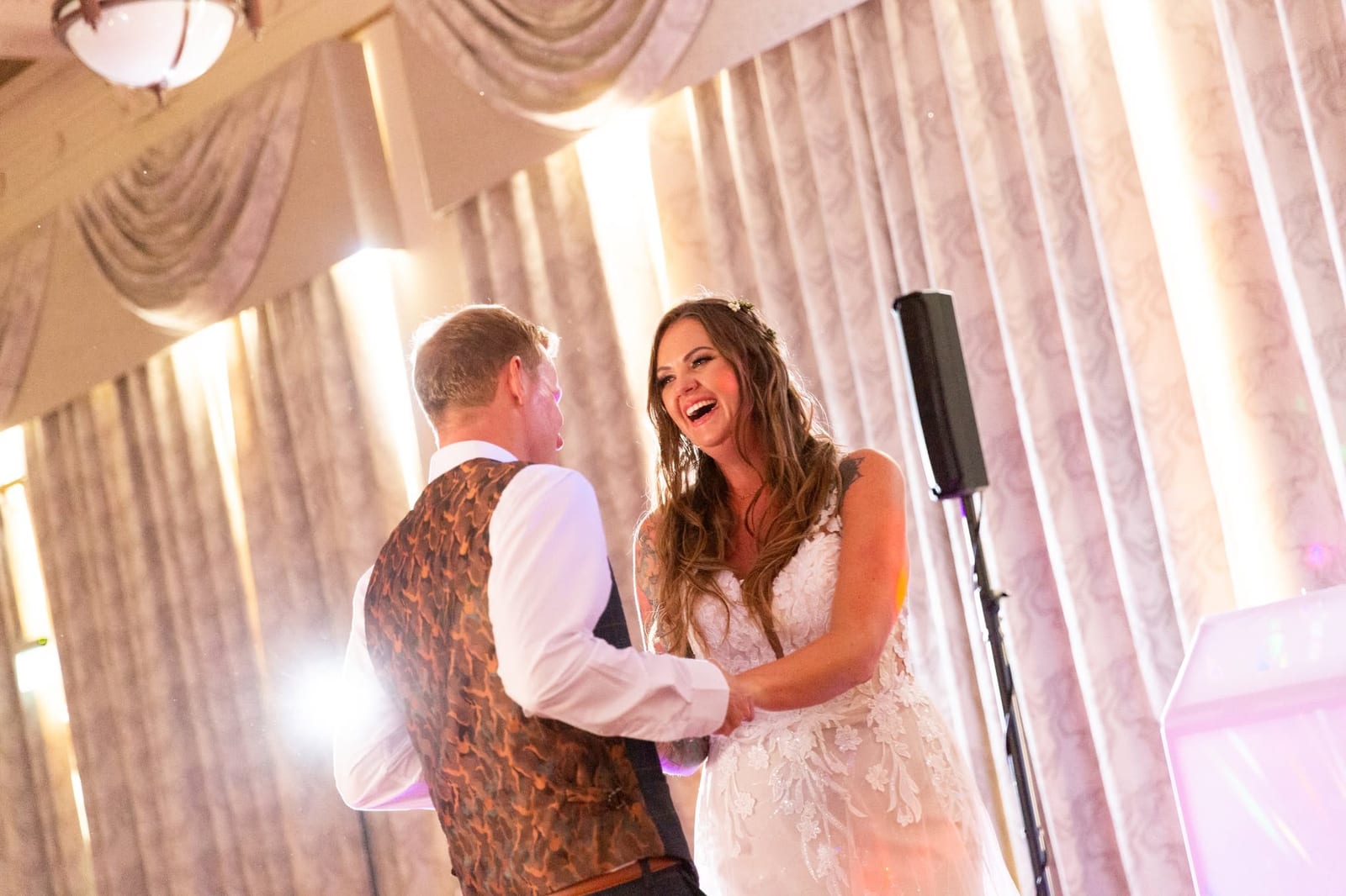 A bride laughing with her groom during their first dance