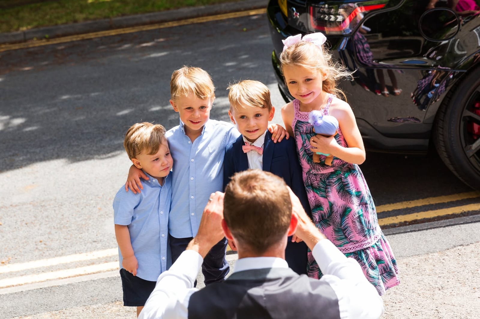Children smiling together for a photograph outside a wedding