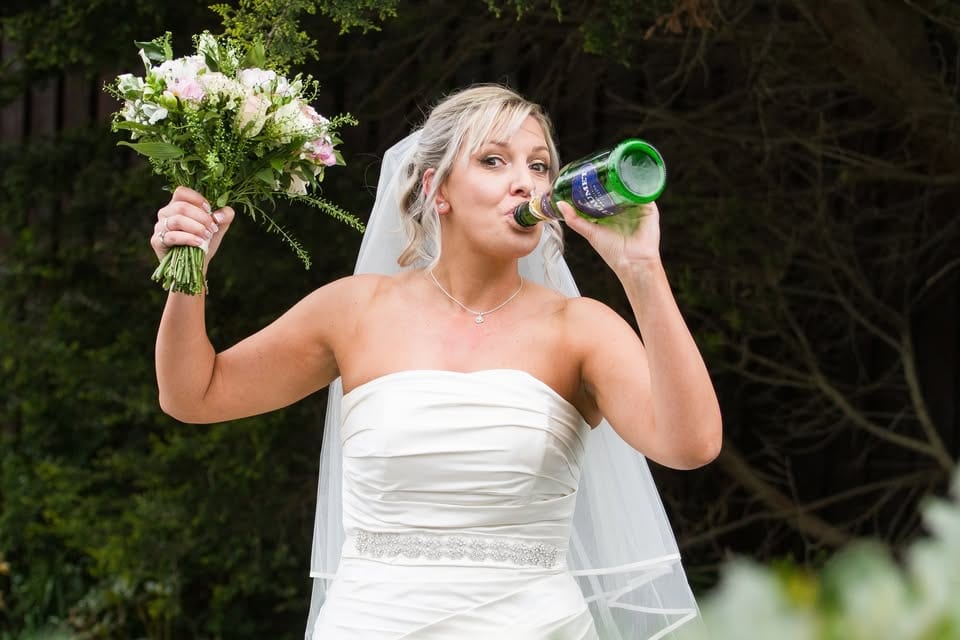 A bride raises her bouquet and takes a celebratory drink